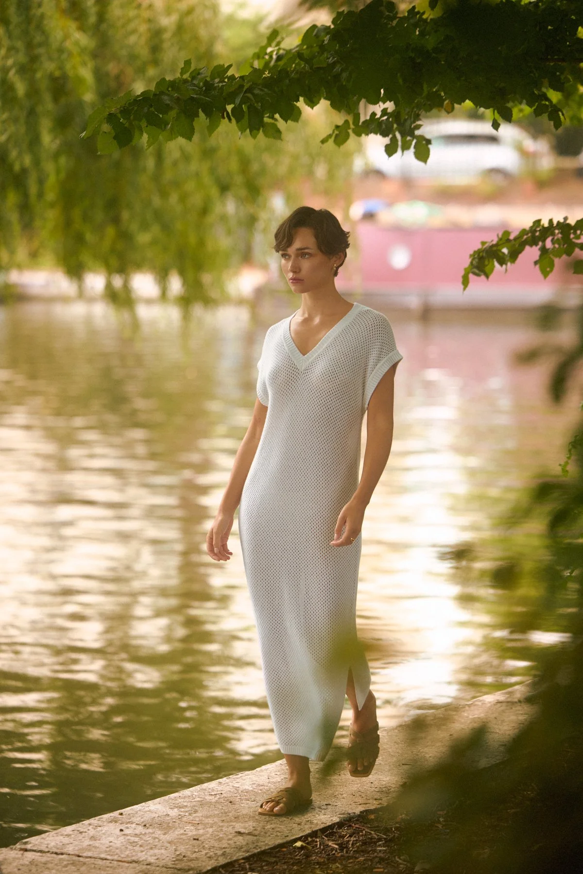 Knitwear lookbook: model in a white knit dress walking a riverbank