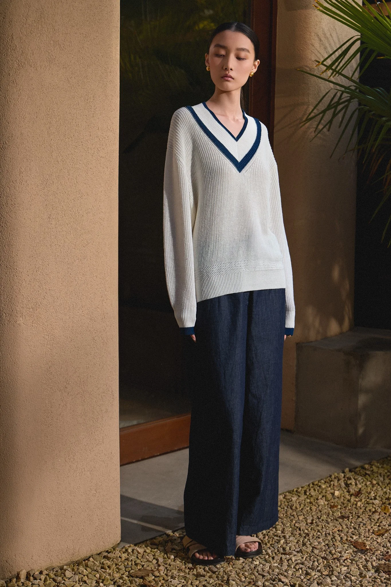 Fashion lookbook: model in a white V-neck jumper shot outdoors at night