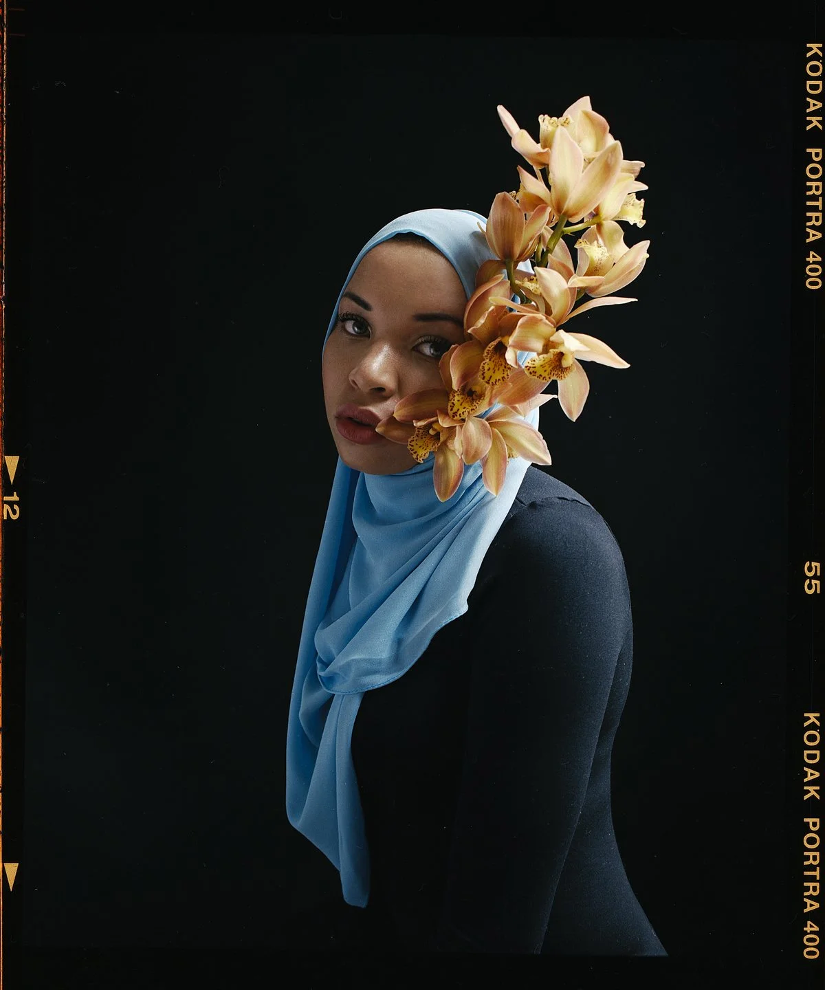 Studio portrait: hijab dressed with peach orchids against black