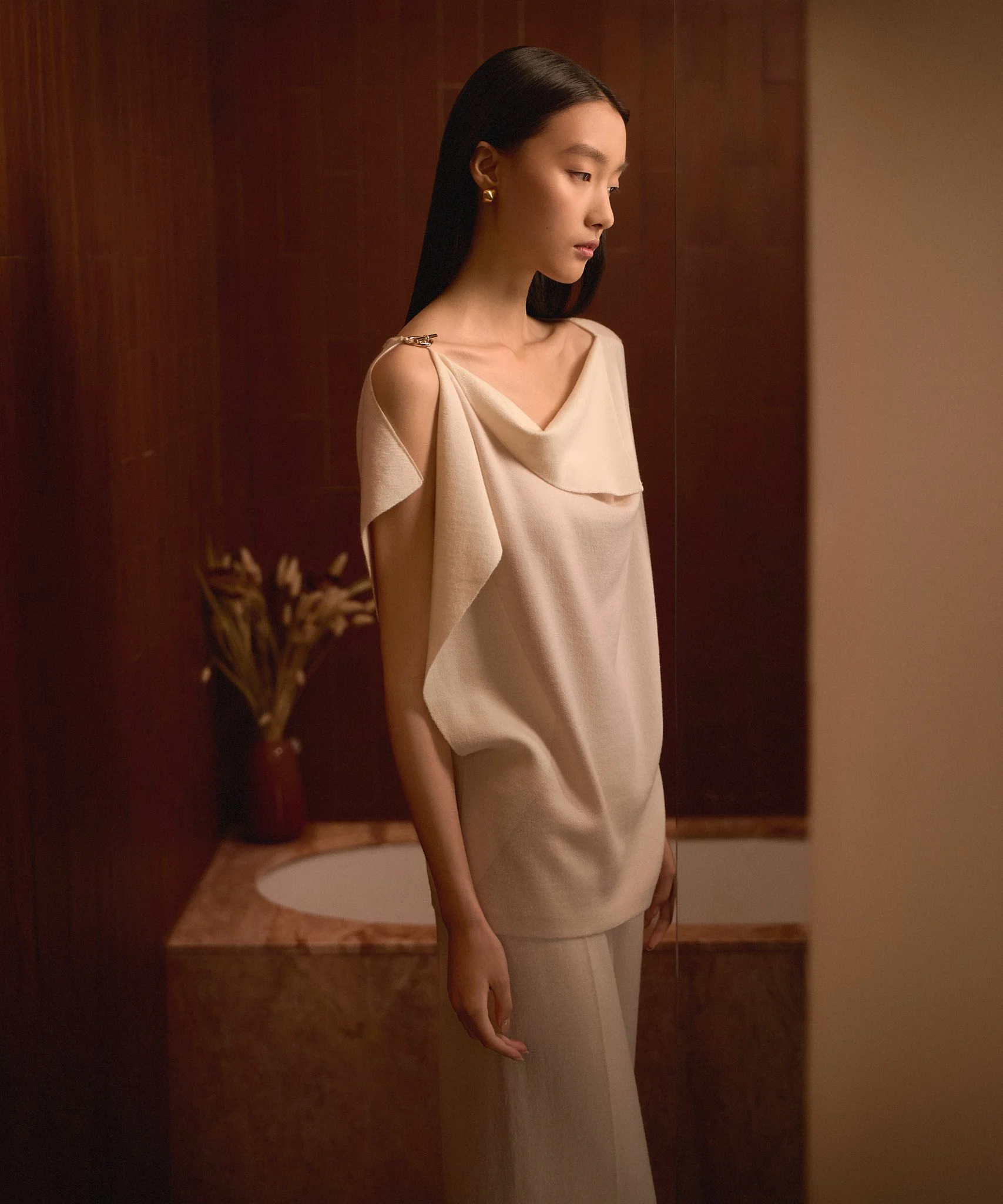 Fashion lookbook: model in a cream dress with shoulder detail and gold earrings