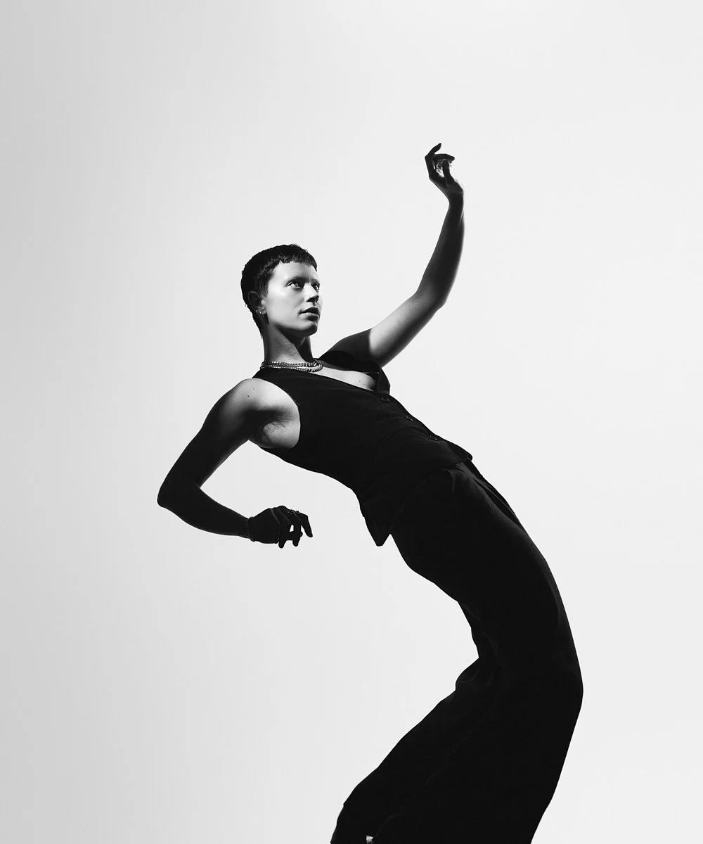 Model test in black and white: full-length pose with a raised arm