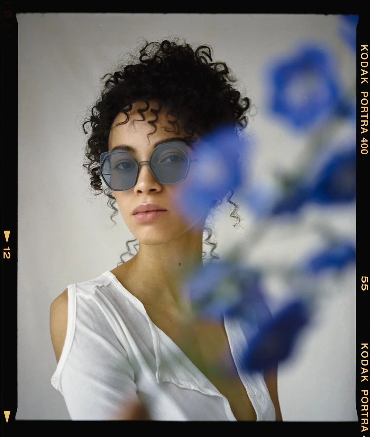 Eyewear campaign: model in oversized blue sunglasses and a white vest