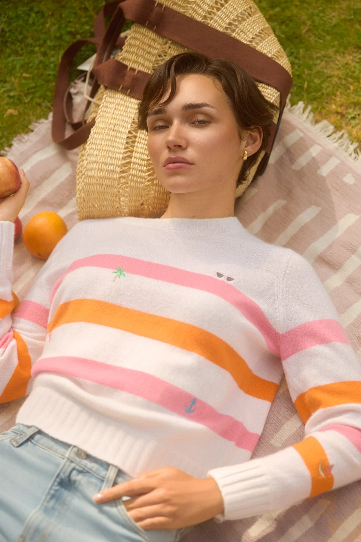 Knitwear lookbook: model lying on a striped blanket on the grass