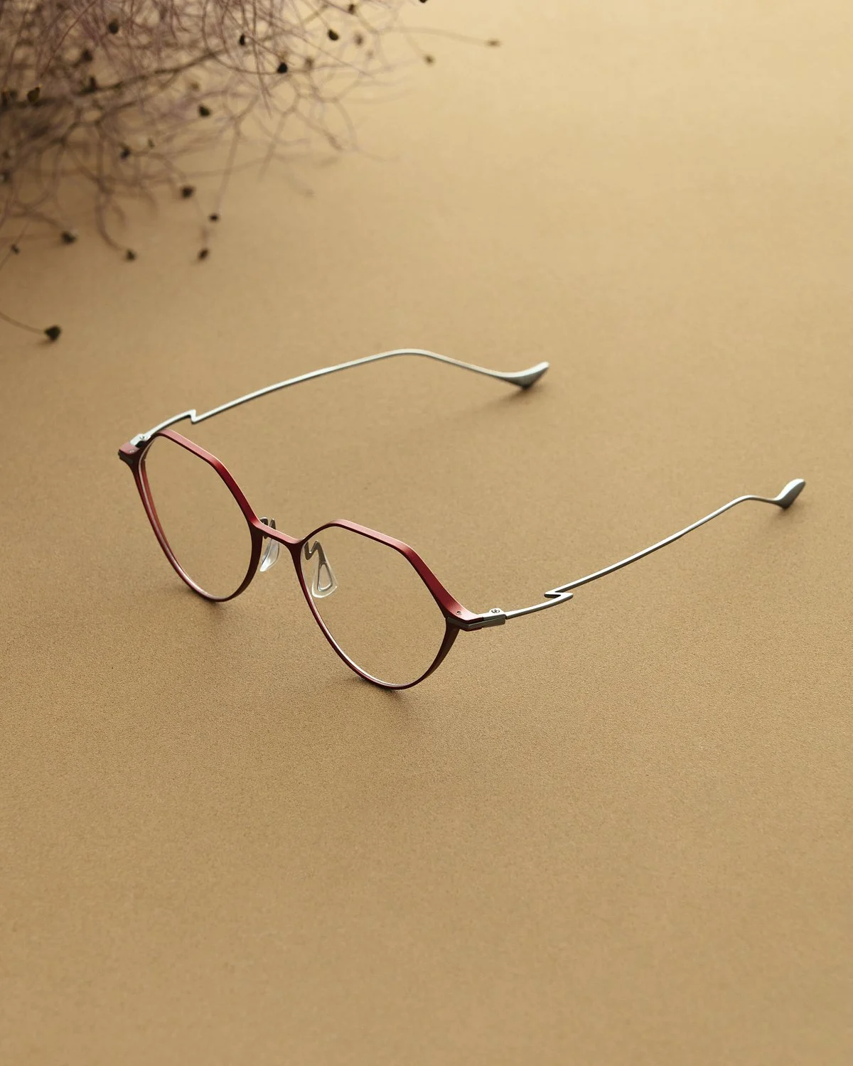 Eyewear still life: pink and silver frames on tan with dried flowers