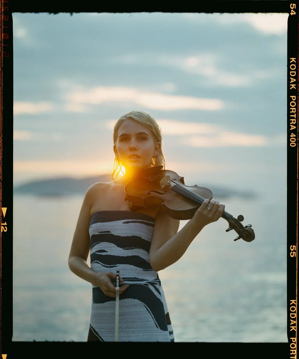 Music portrait: violinist at sunset holding her violin and bow