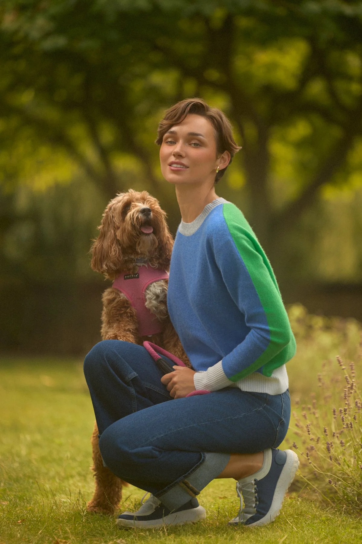 Knitwear lookbook: model kneeling in a blue jumper with green sleeves