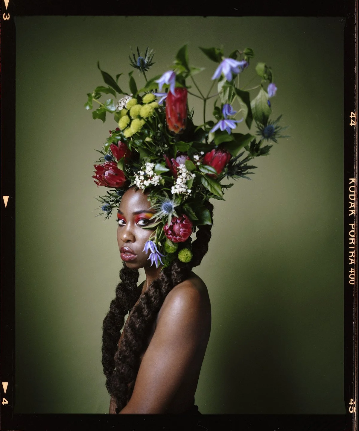 Studio beauty portrait: long braids with an elaborate flower and foliage headpiece
