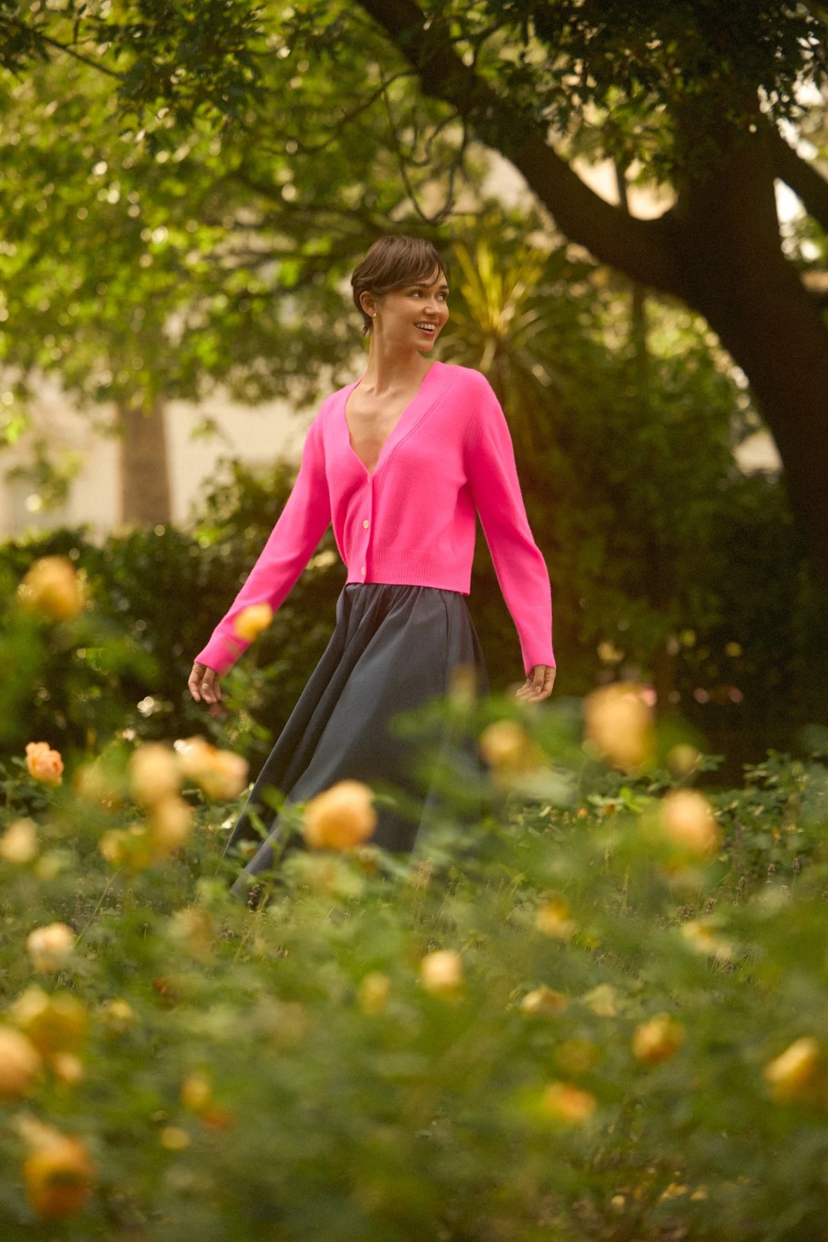 Knitwear lookbook: model in a pink cardigan walking through a garden
