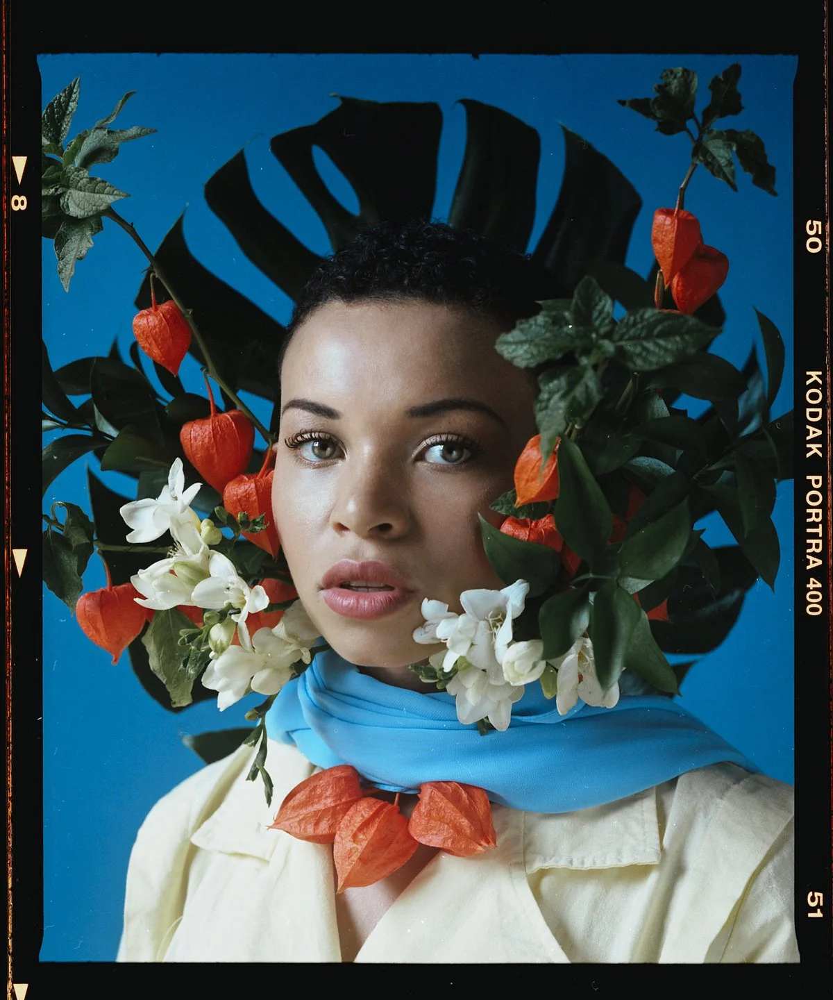 Floral studio portrait: model framed by orange and white flowers and foliage