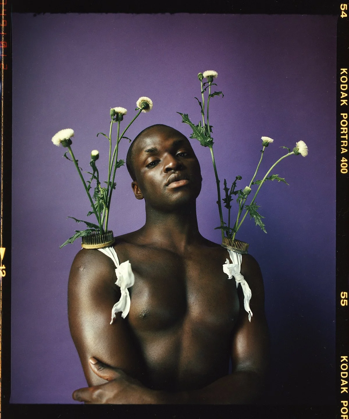 Studio portrait: white daisies pinned at the shoulders against purple