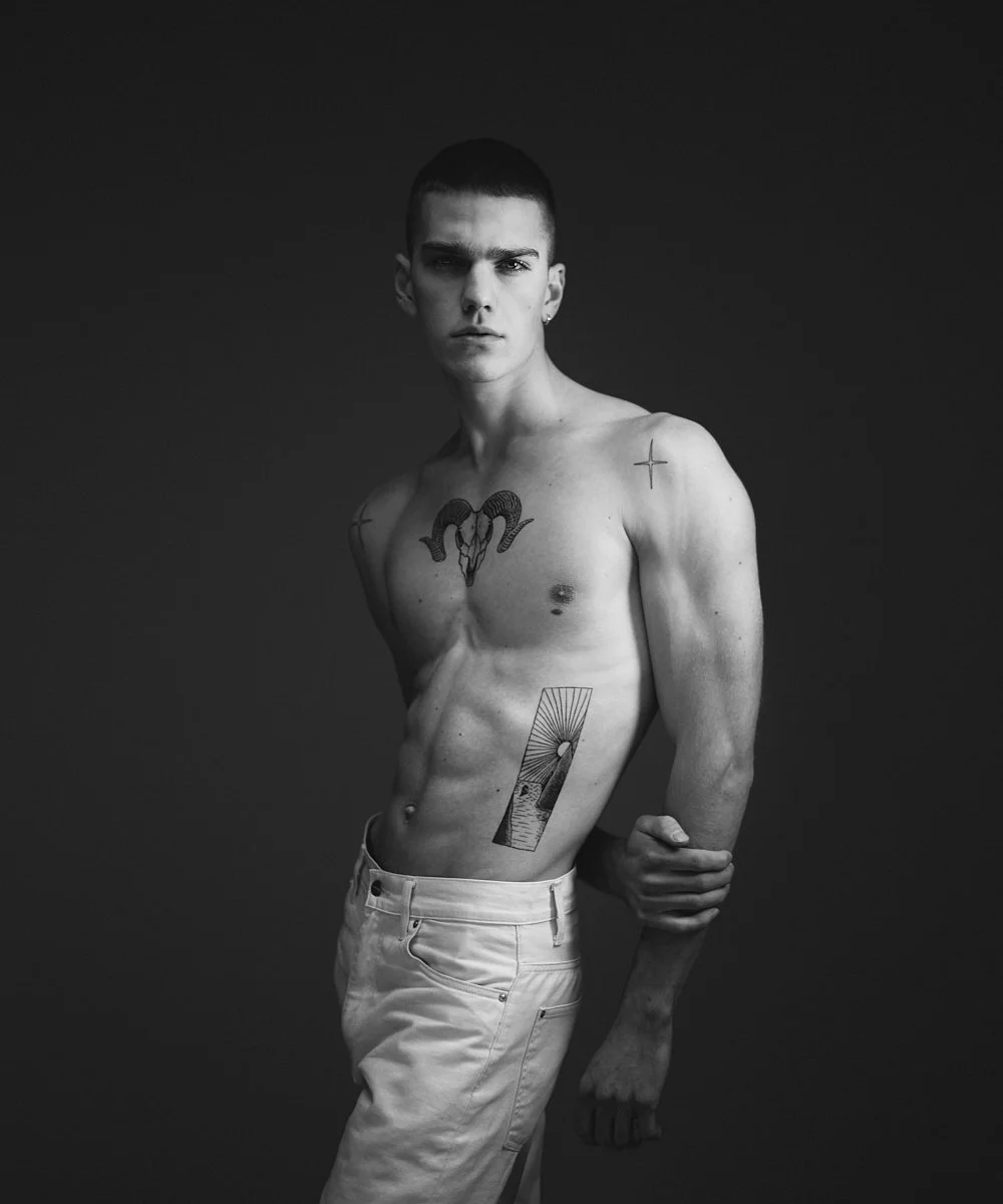 Model test in black and white: tattooed portrait in pale trousers