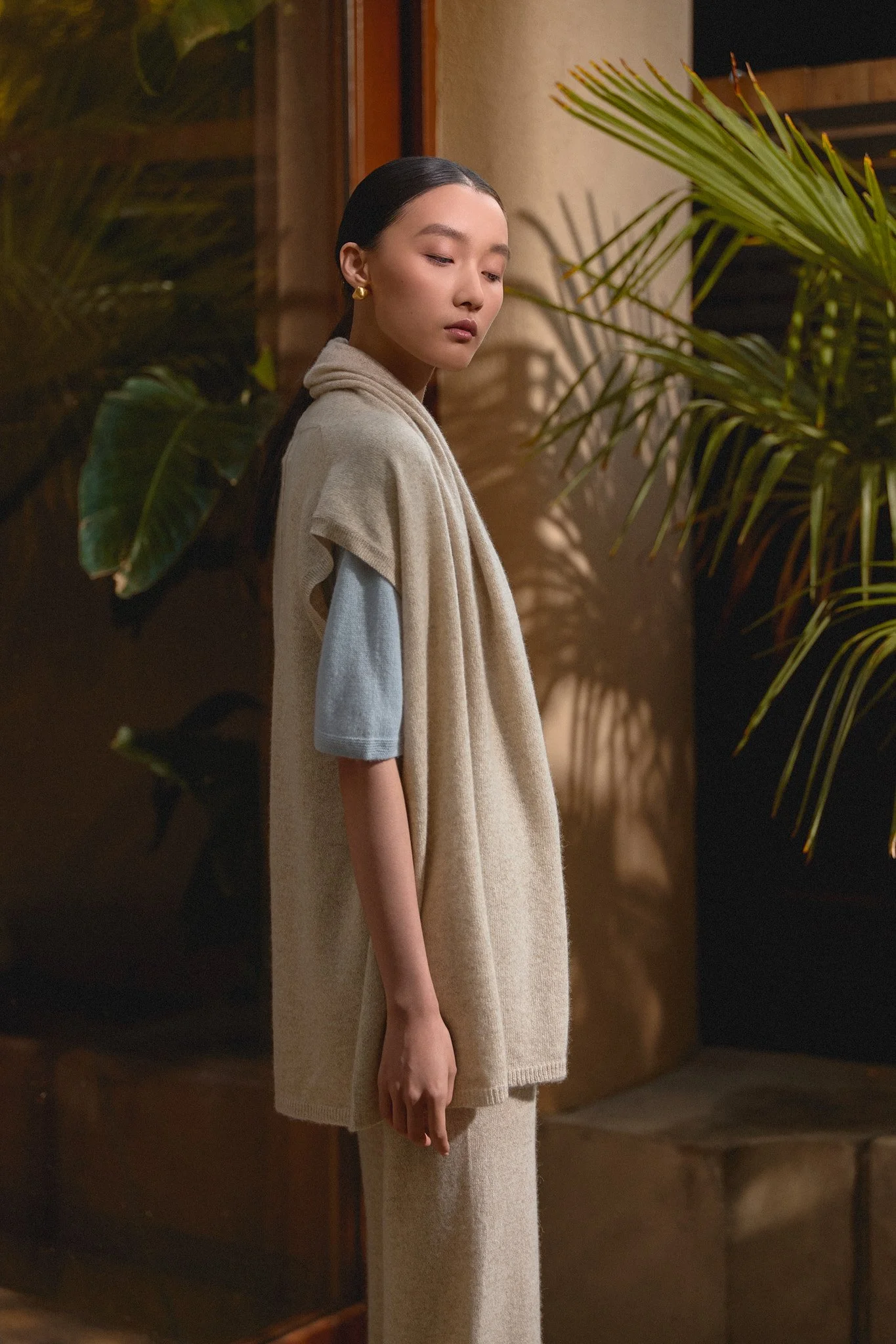 Fashion lookbook: model in neutral tailoring beside plants and wood panelling