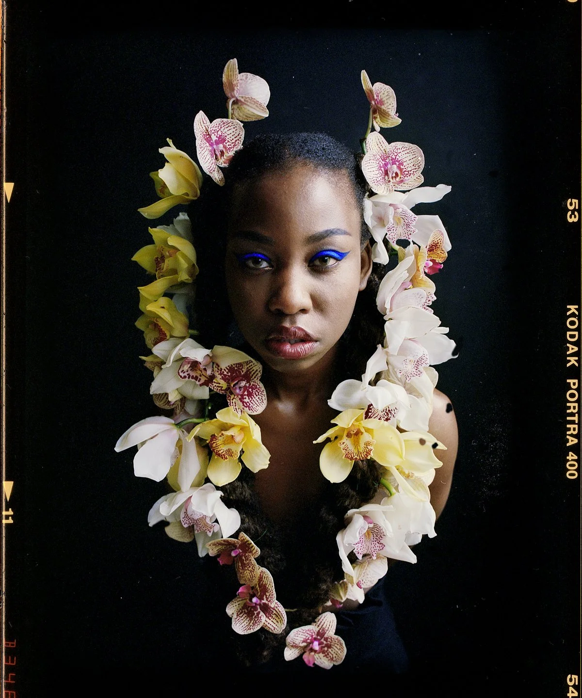 Studio beauty portrait: model in a bank of white, yellow and pink orchids