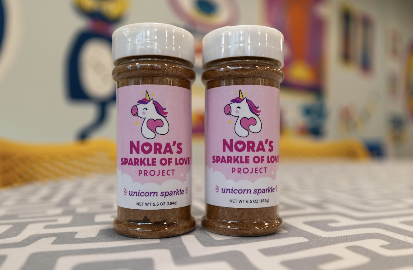 Multiple jars of Nora's Unicorn Sparkle cinnamon sugar spread on store shelf.