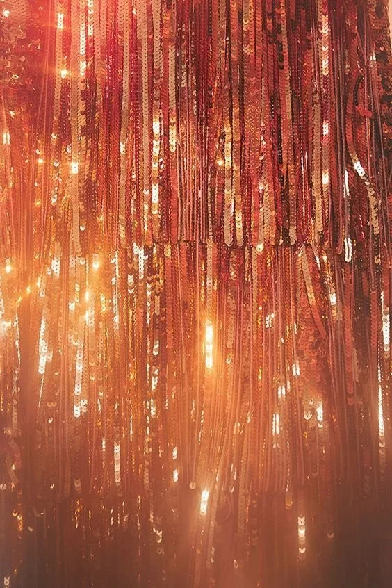 Close-up of shiny, orange and red metallic fringe or sequin fabric.