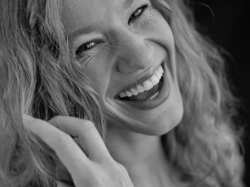 Schwarzweißfoto einer lächelnden Frau mit lockigem Haar.