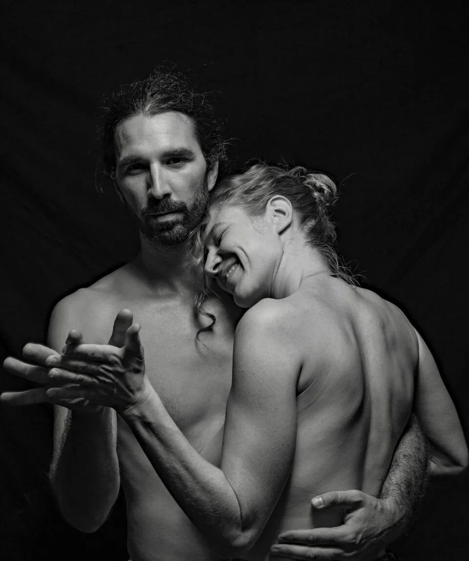 Schwarz-weiß-Foto eines Mannes und einer Frau in einer Umarmung vor dunklem Hintergrund.