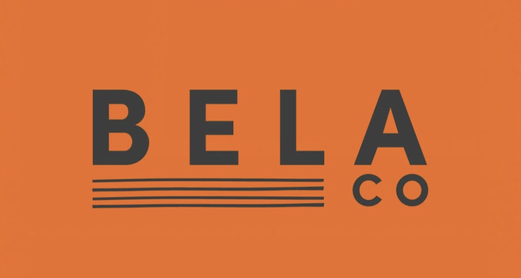 Logo with the text 'BELA CO' on an orange background, with the word 'BELA' in large black letters and a series of five black horizontal lines underneath, with 'CO' written vertically beside the lines.