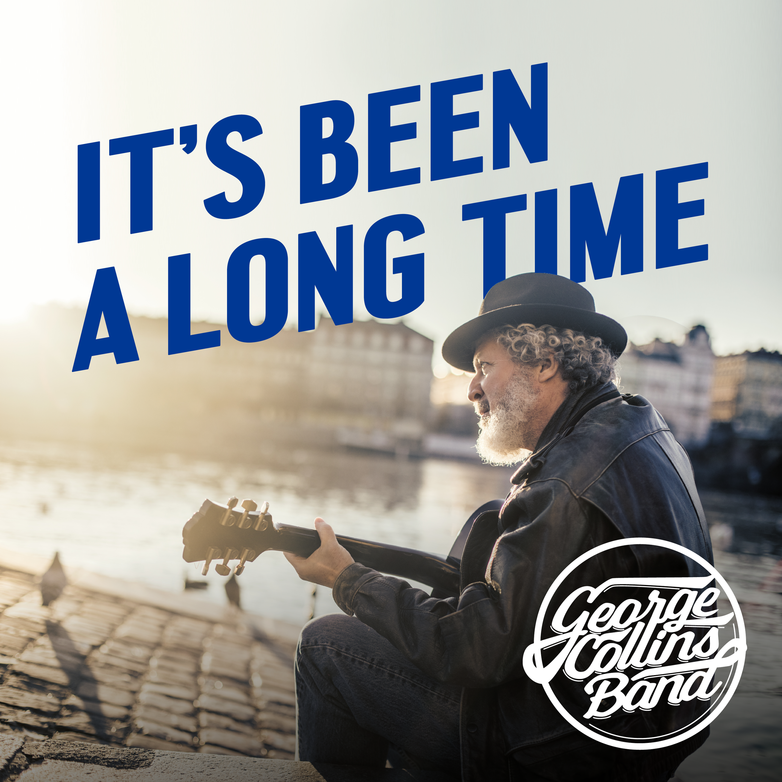 A person with curly hair and a hat playing an acoustic guitar by a waterfront during sunset, holding a sign that says "It's Been A Long Time" and a circle with the words "George Lewis Band."