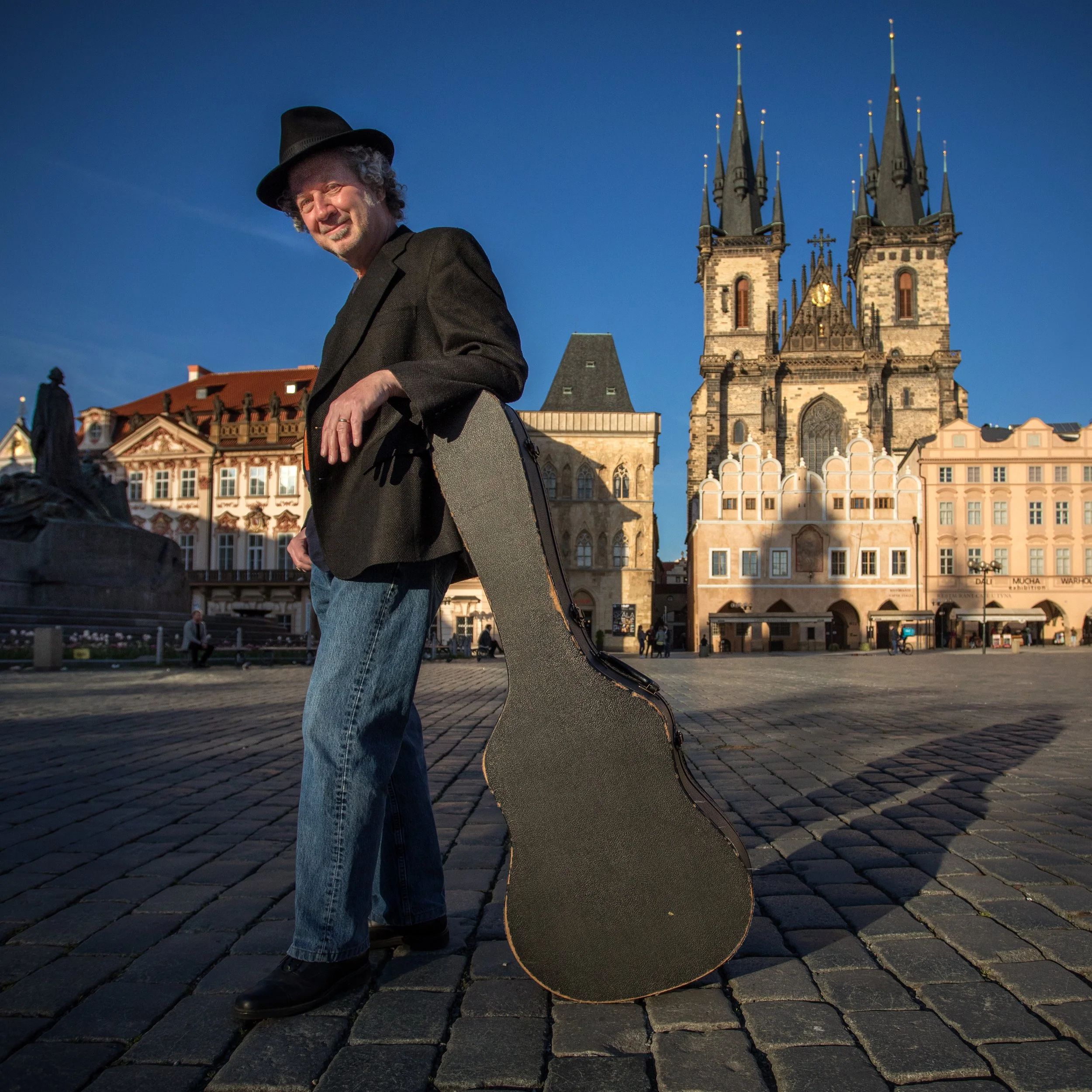 George Collins holding a guitar case in Old Town Square, Prague