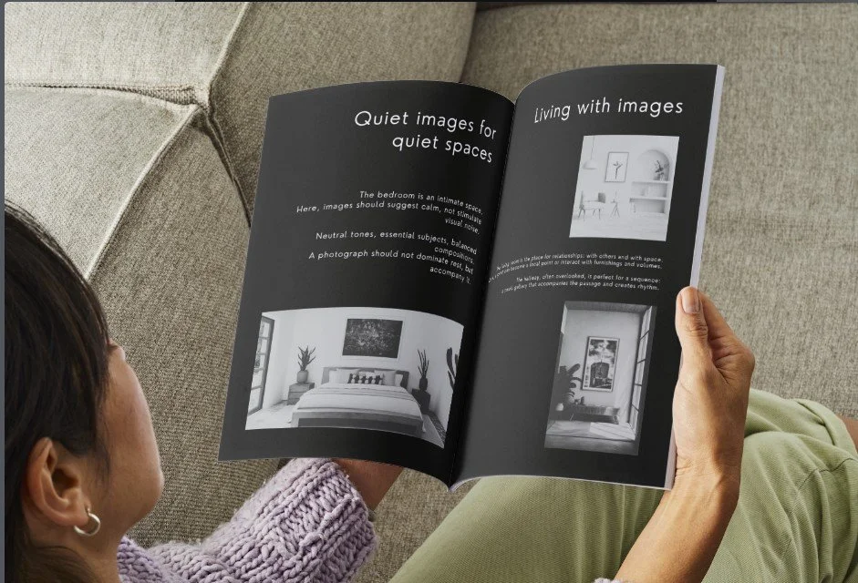 Una persona che tiene in mano un opuscolo aperto sulle immagini di ambienti domestici, con testo in inglese e fotografie di stanze in bianco e nero.