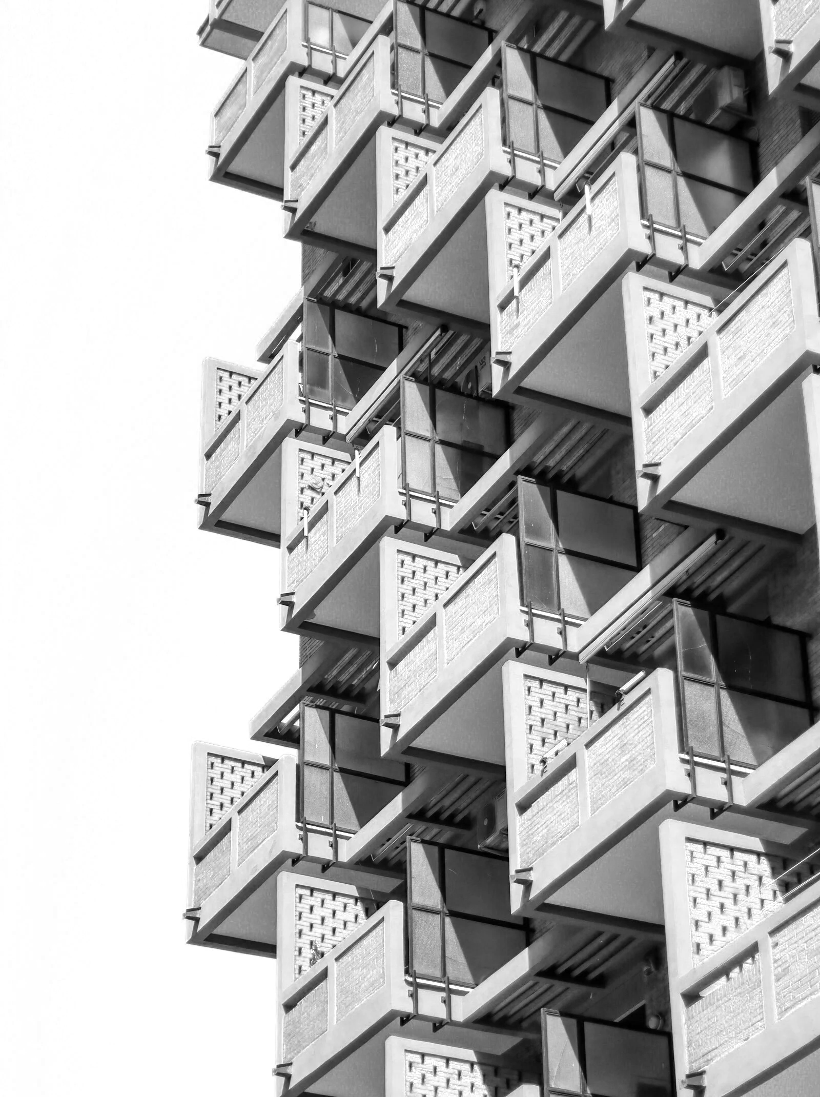 Immagine di un edificio con numerosi balconi sovrapposti e strutture in vetro, in bianco e nero.