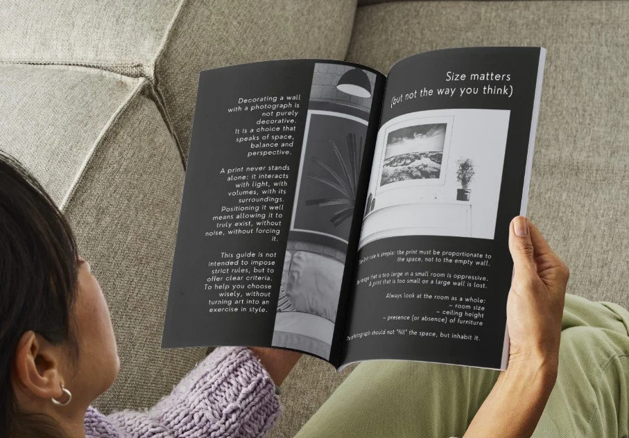 Una persona che legge un magazine con testo e immagini su arredamento e dimensioni degli ambienti, seduta su un divano beige.