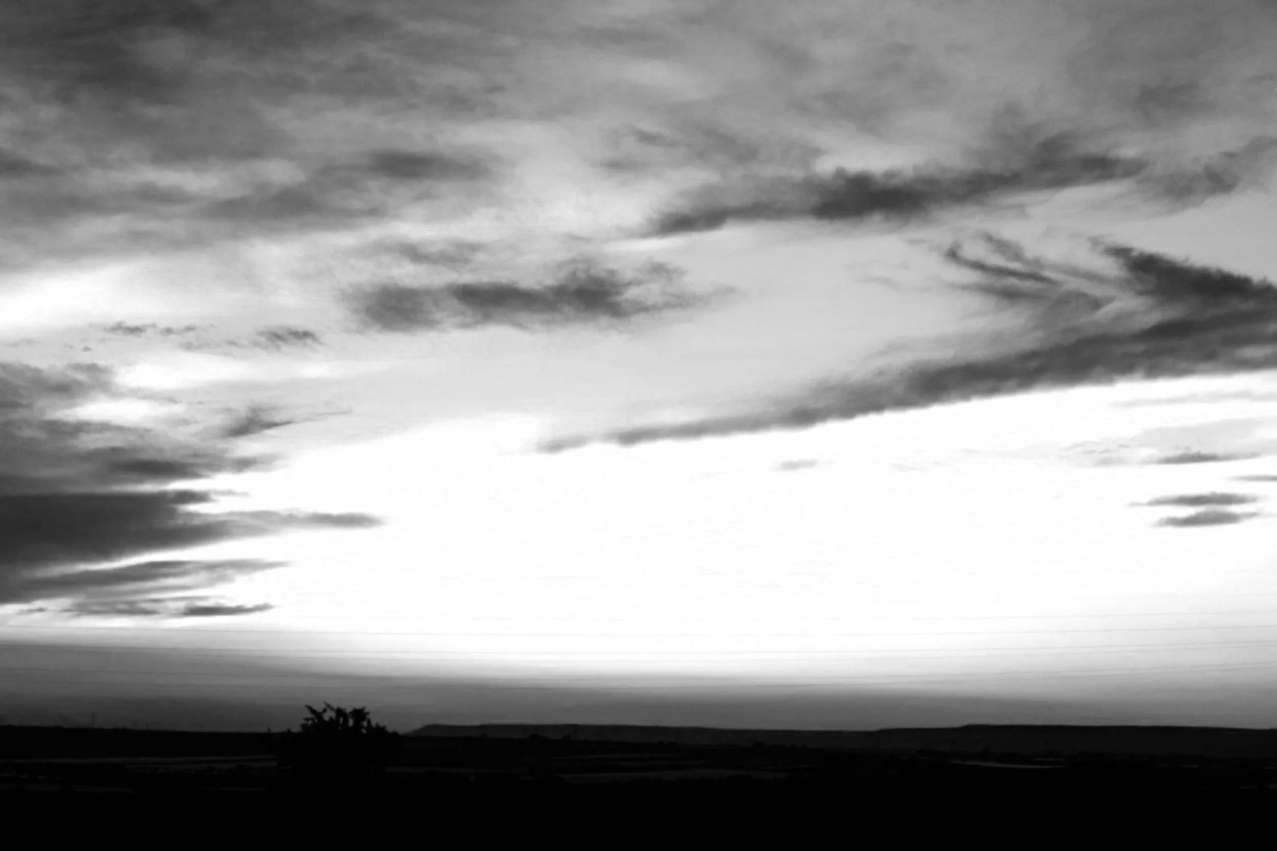 Paesaggio con cielo nuvoloso e orizzonte lontano, in bianco e nero.