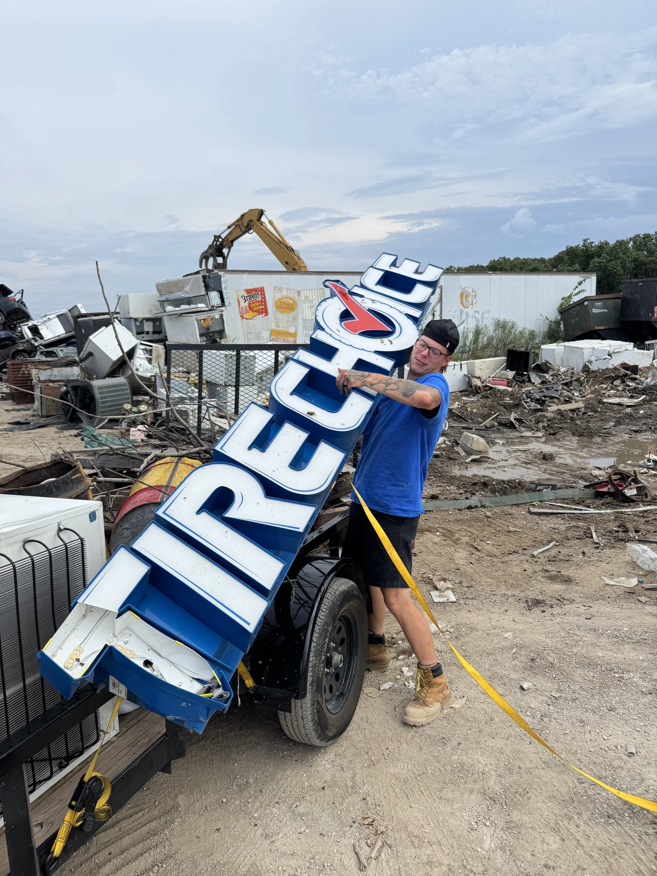 Business owner holding a broken sign that was removed from a tire choice for commercial  junk removal. Showing that we recycle all the items that we can.