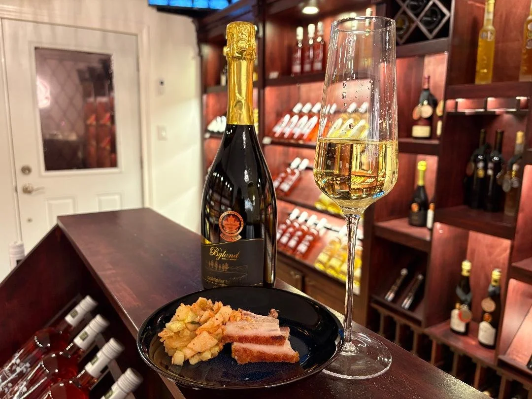 A plate of roast pig with pear, Kimchi and cucumber salad with a class of Byland Estate Chardonnay