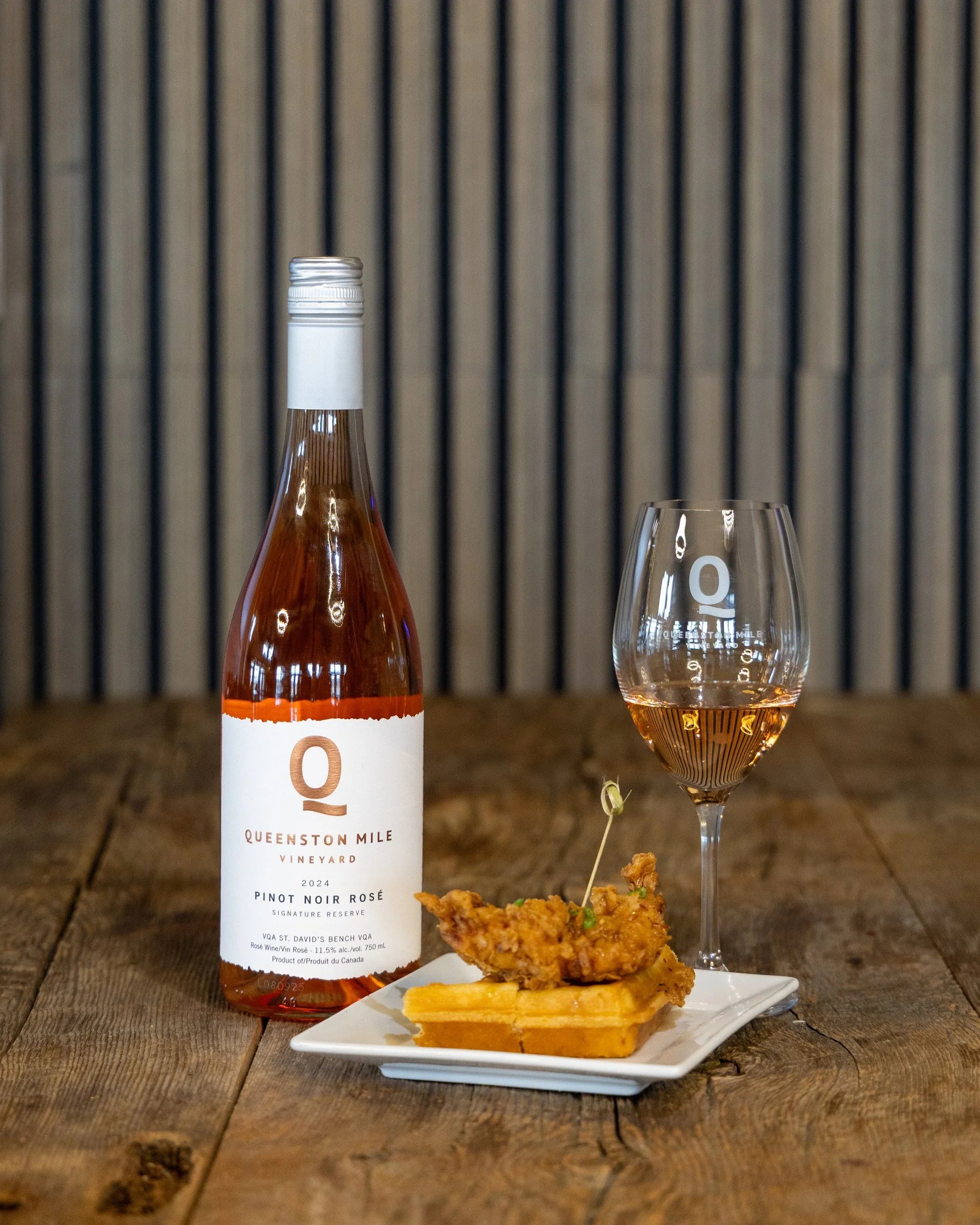 A plate of chicken and waffles with a class of Queenston Mile Pinot Noir Rose