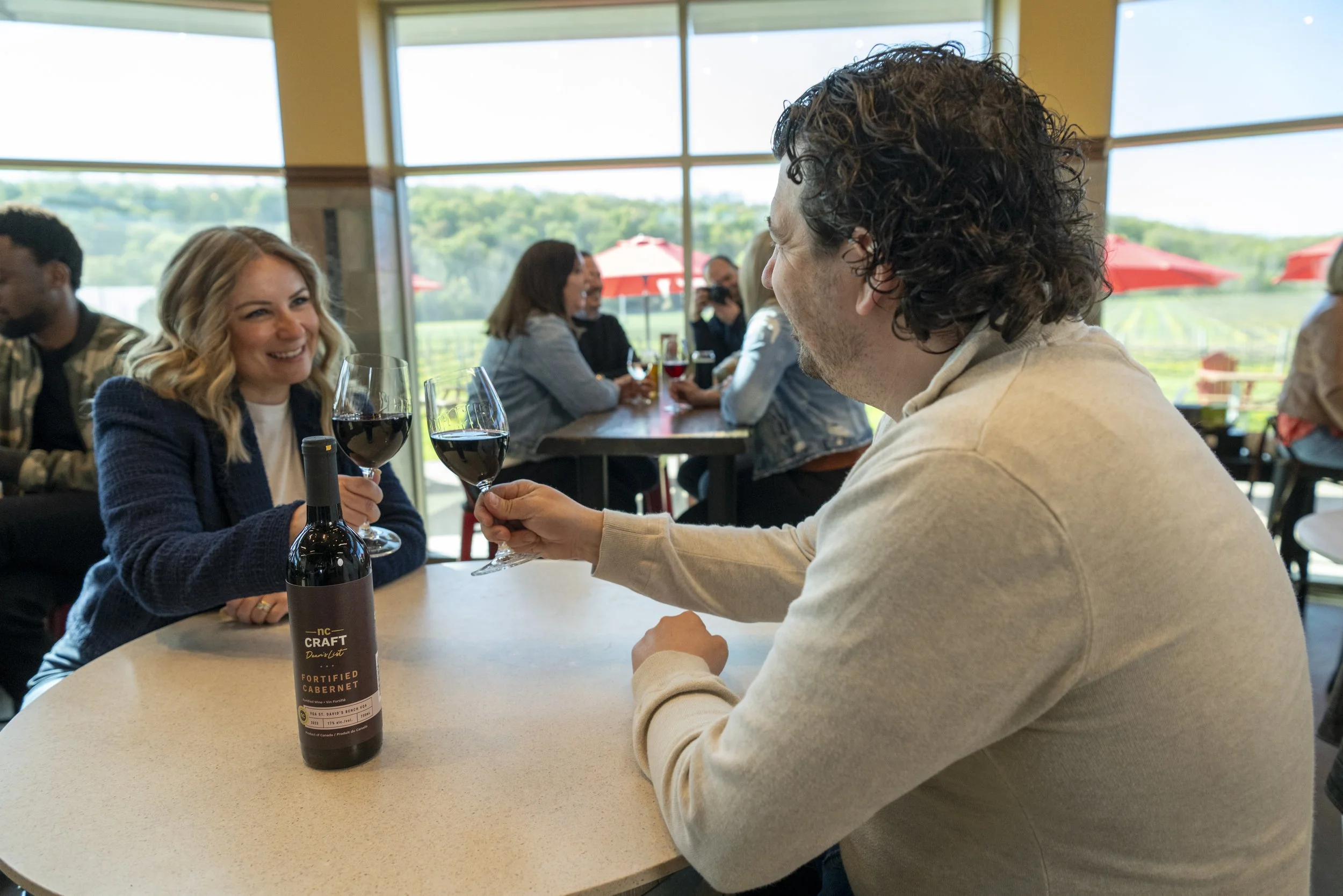 Two people holding glasses of red wine
