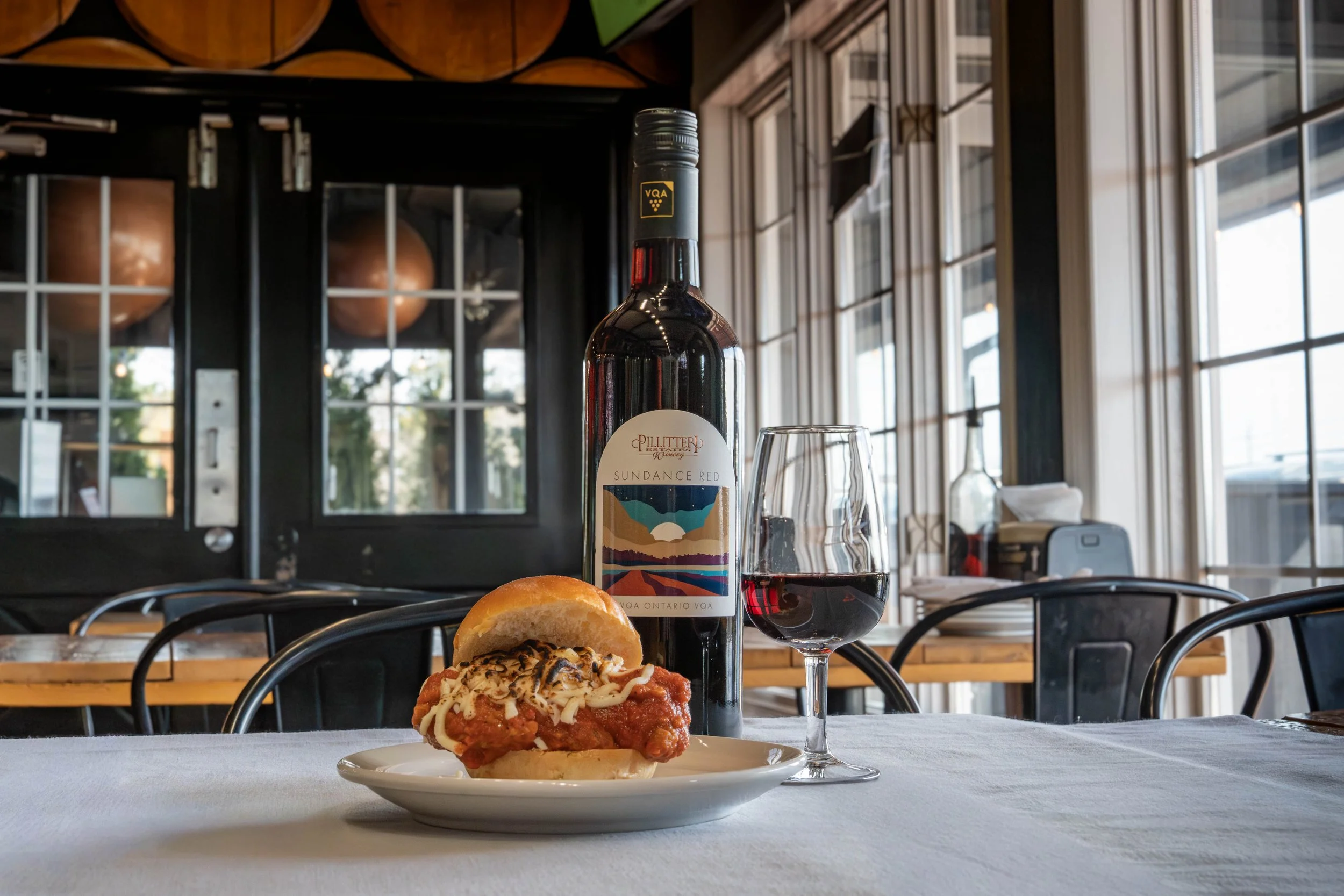 Chicken parmesan on a bun and a glass of Pilliteri Estates 2023 Sundance Red Wine
