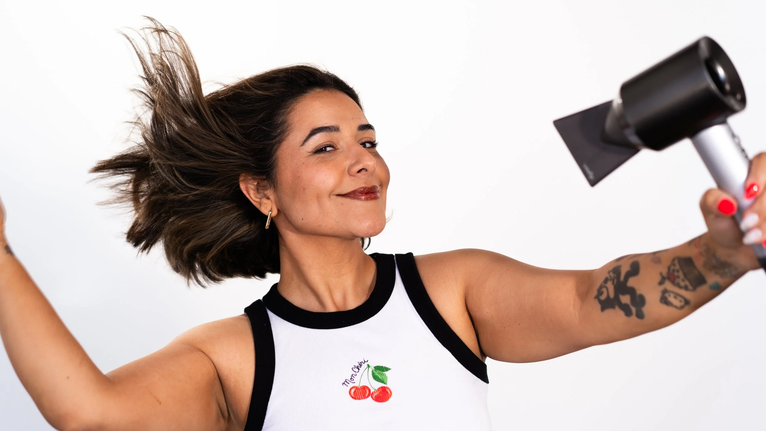 Maria from Honey Bee Color Collective with short brown hair mid-toss, smiling against a white background.