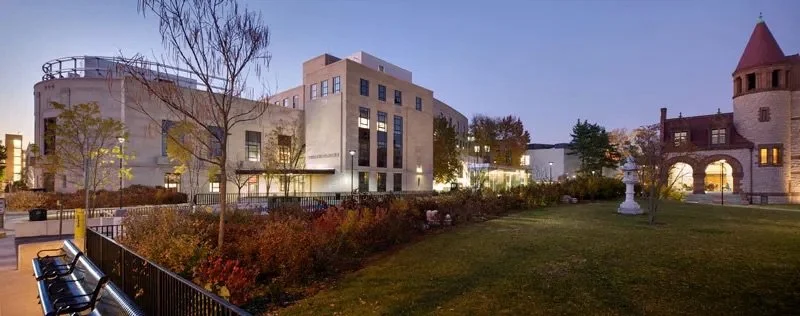 Exterior view of university buildings and a garden at dusk.