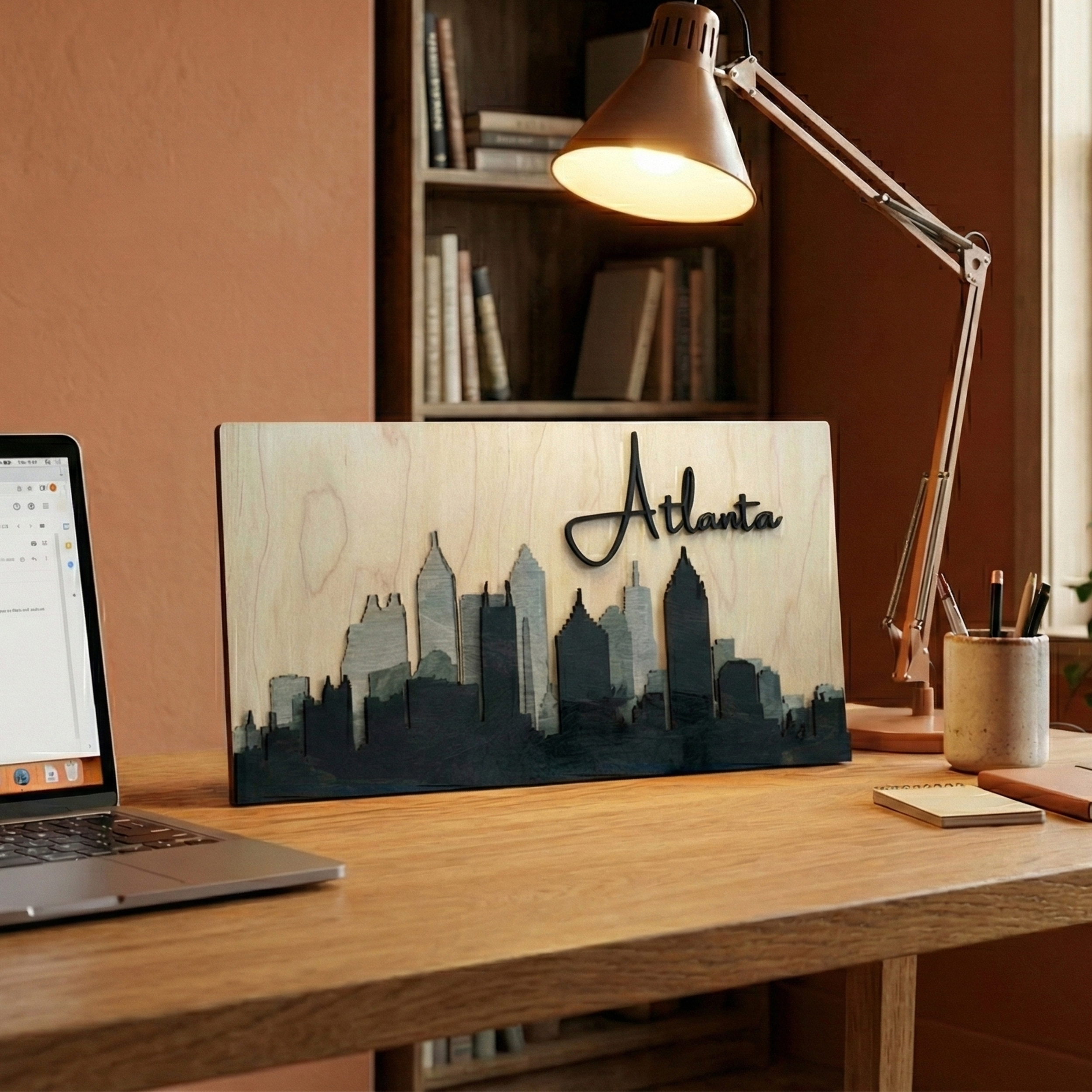 3D grey Atlanta wood skyline art on a wooden office desk with a laptop and modern lamp.
