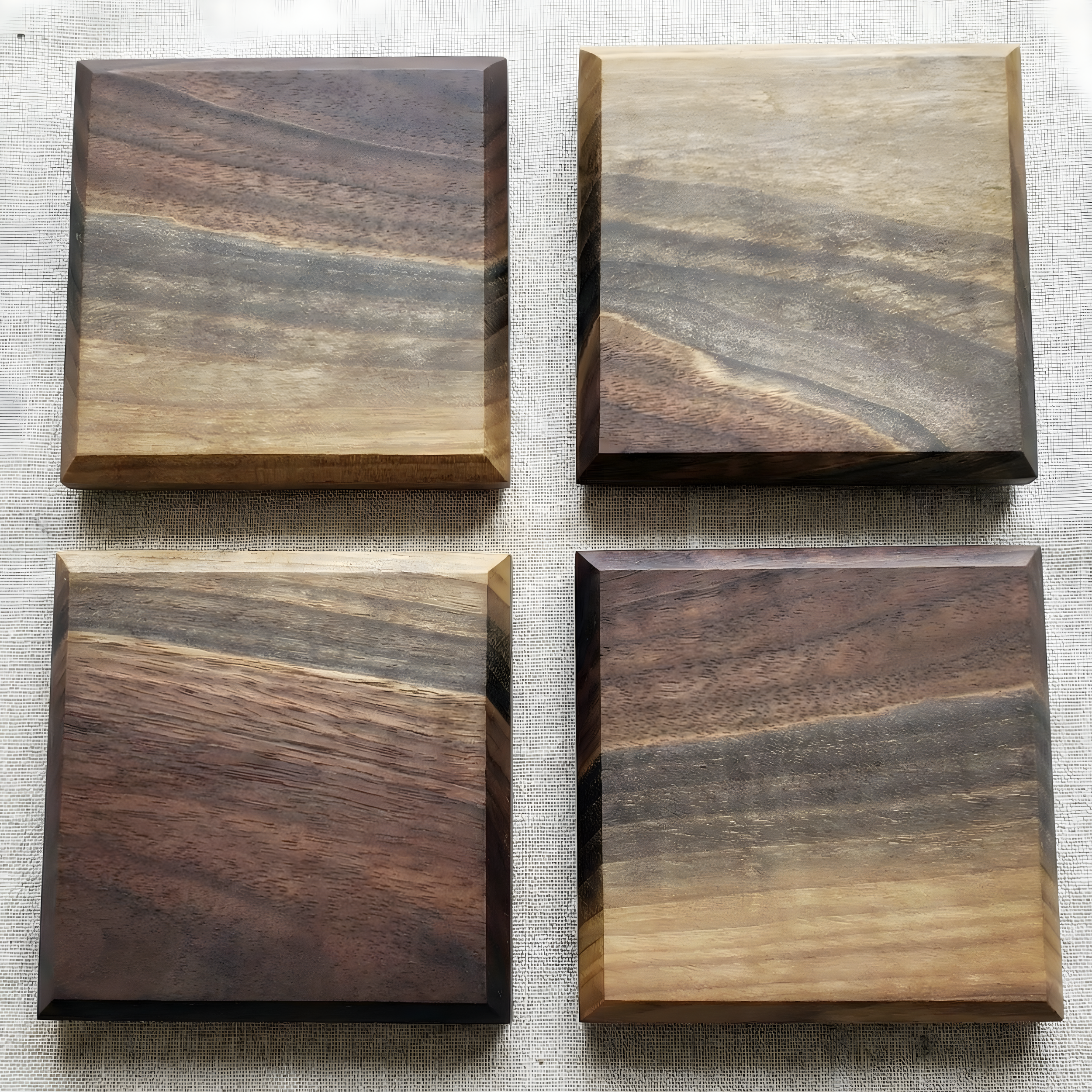 Overhead view of four handcrafted solid walnut coasters showing unique wood grain patterns.