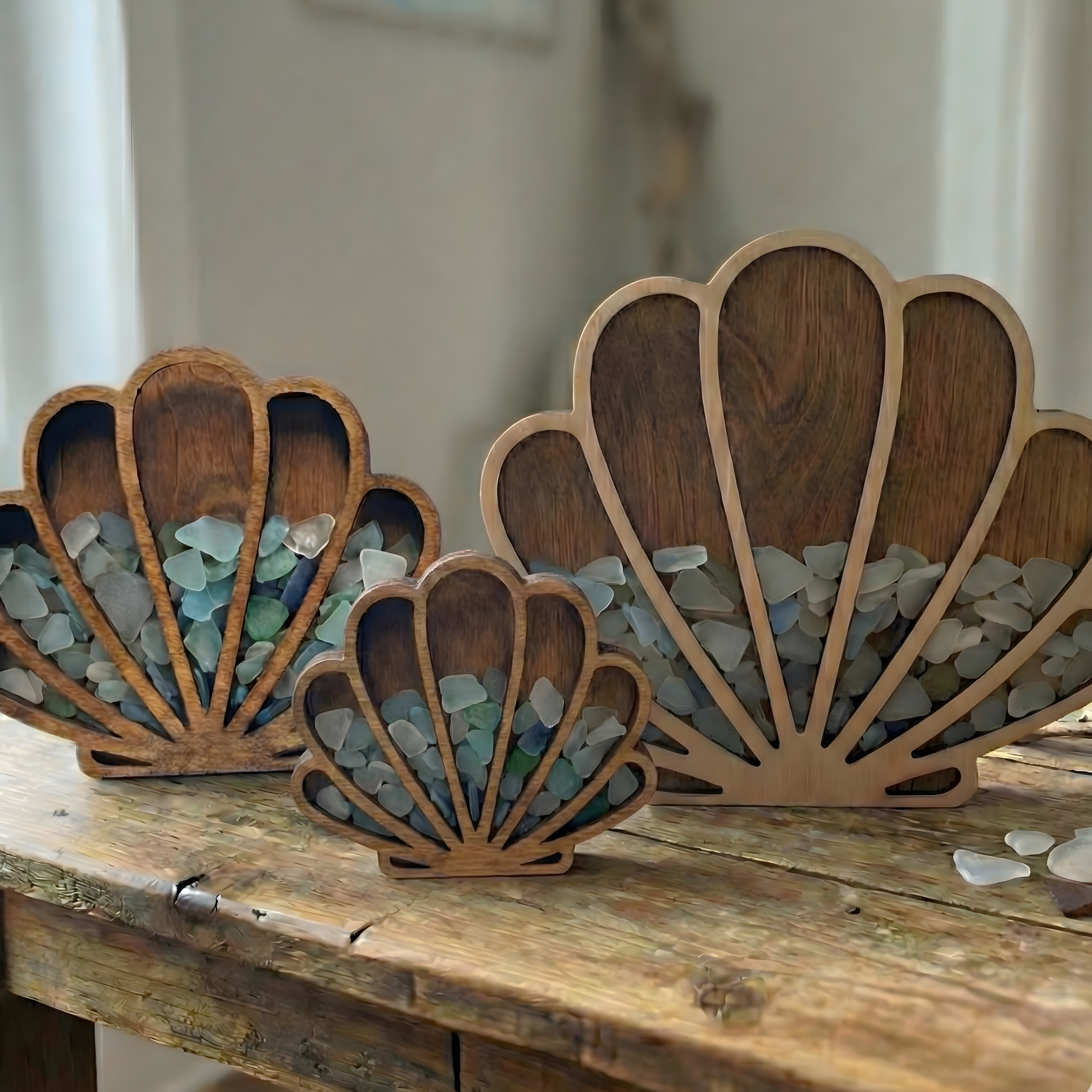 Three seashell wooden frames filled with sea glass in various sizes displayed together.