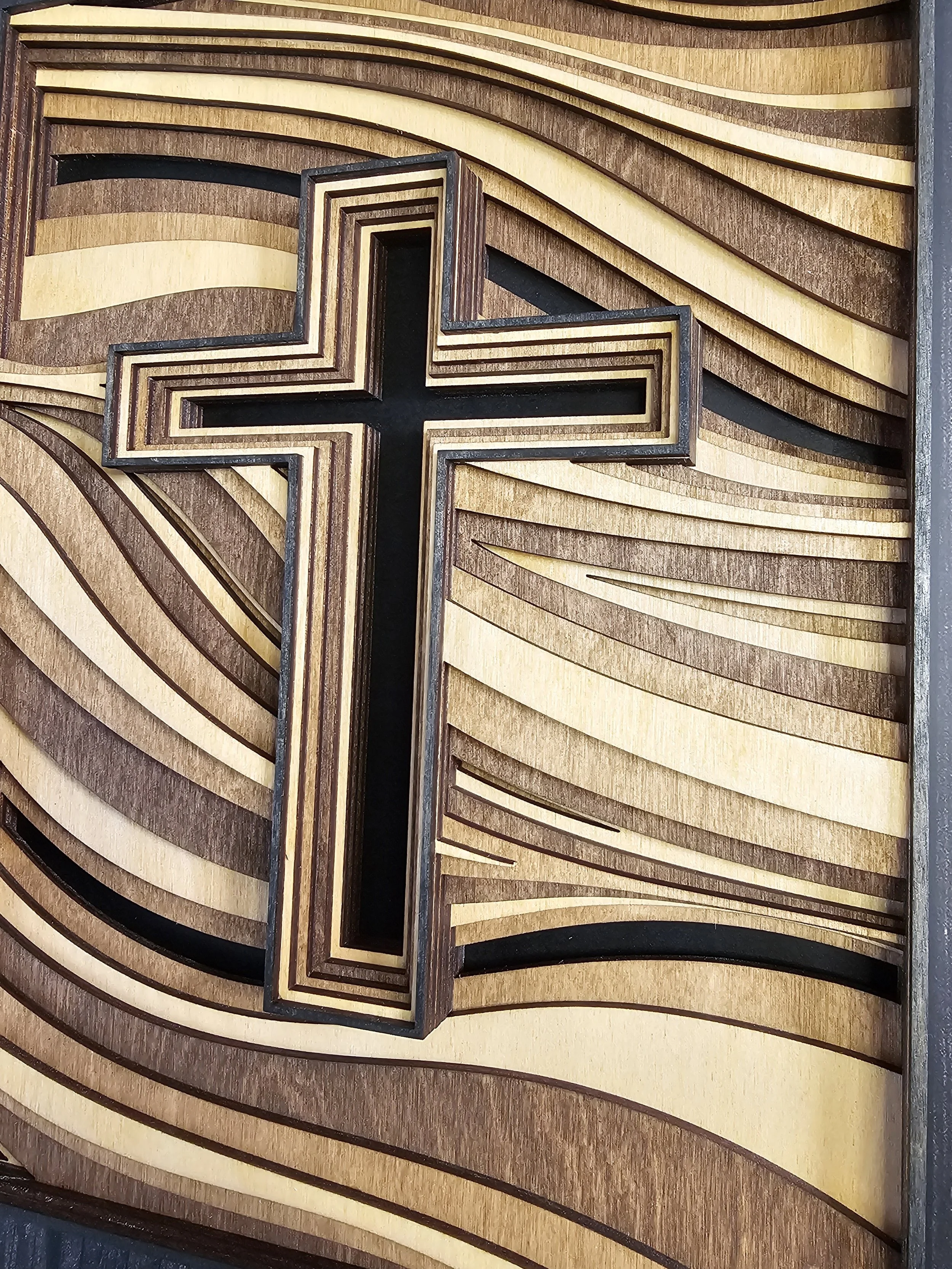 Close-up of 8-layer handcrafted wood cross showing detailed wavy layers and various brown stain shades.