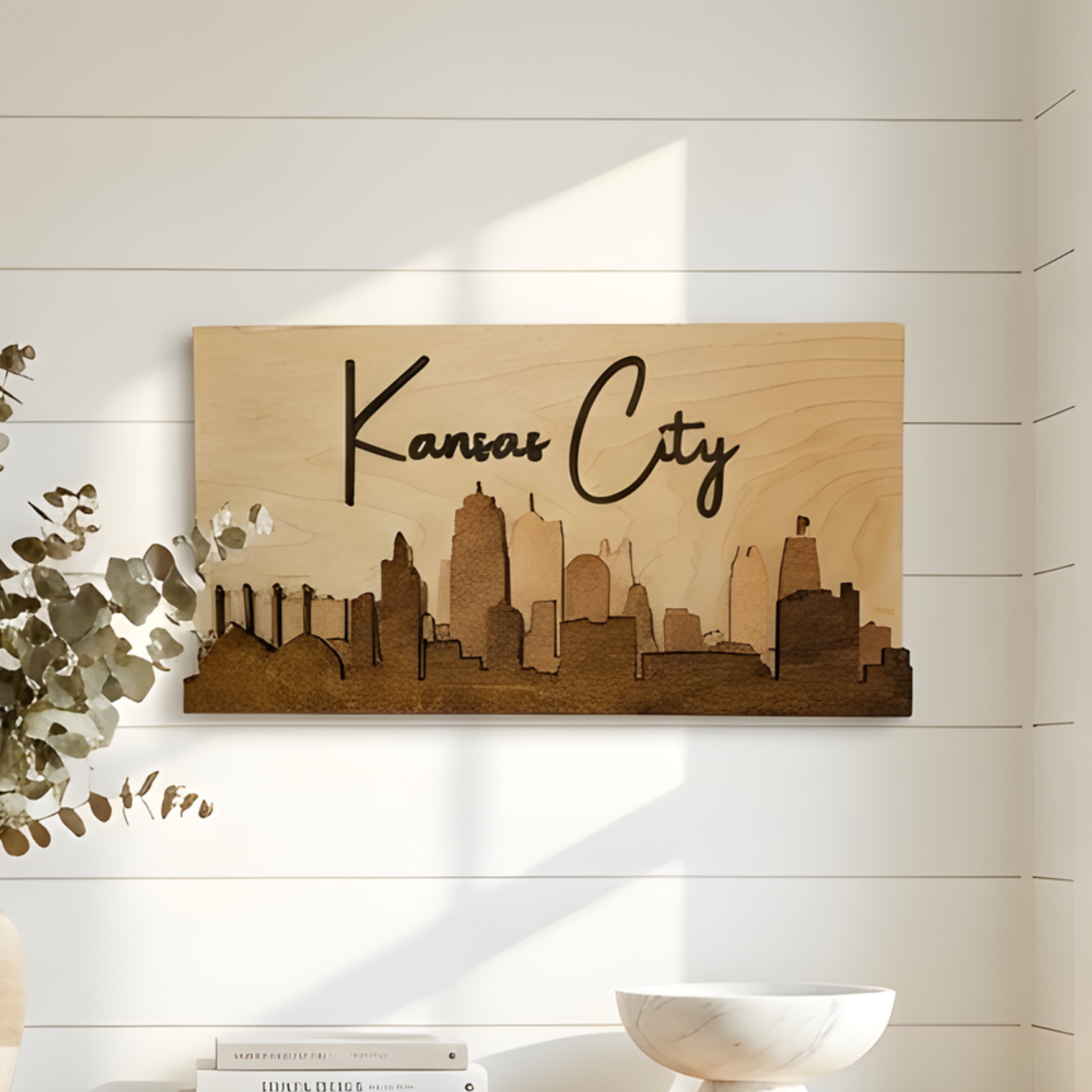 3D wood Kansas City skyline wall art in brown stain hanging on a white shiplap wall with modern decor.