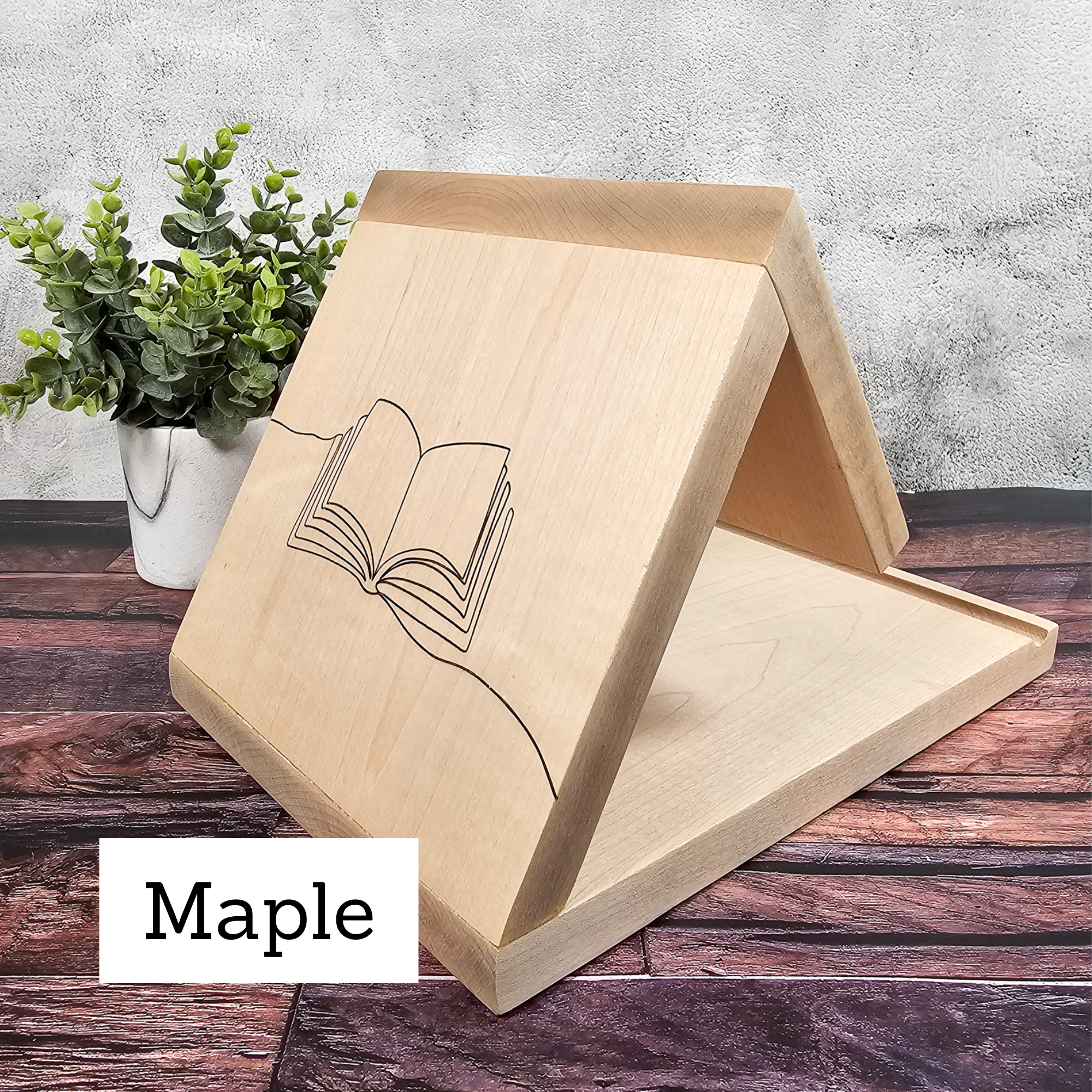 Detailed view of the minimalist open book line drawing engraved on a maple book placeholder.