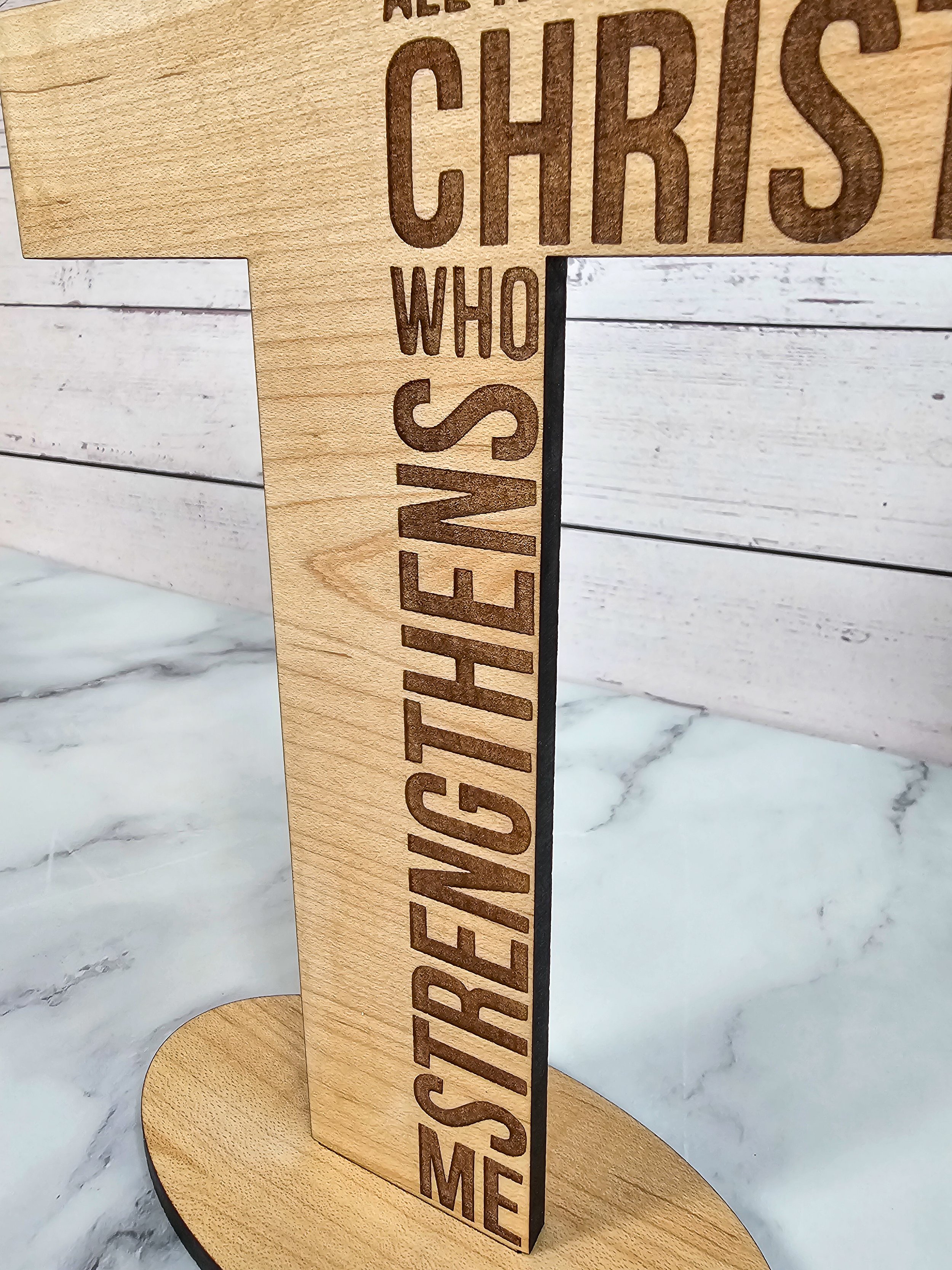 Close-up of high-precision laser engraving on a maple wood cross showing scripture text.