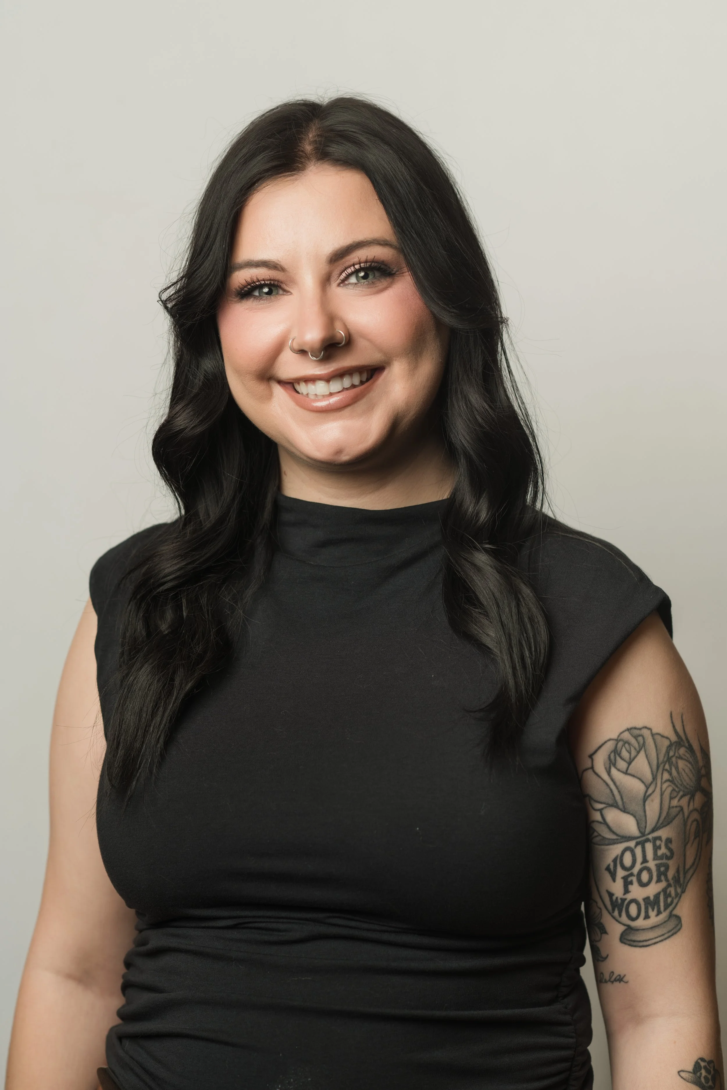Woman in yellow top and black skirt standing next to a red sign for the Book & Sip Club in Nashville, featuring a cocktail glass and books illustration.