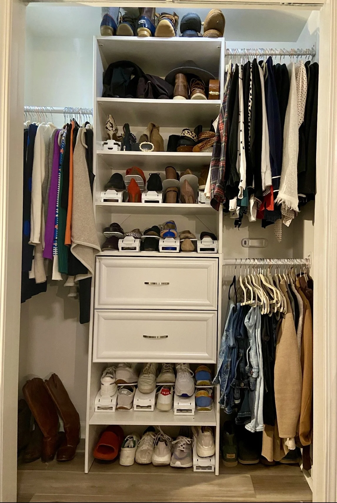 Kansas City Closet with shelves filled with shoes, hung clothes on both sides, and drawers in the center.