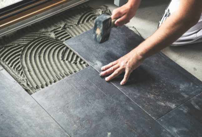 Installing floor tiles using mortar and a rubber mallet in Parry Sound.