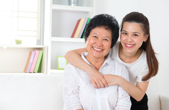 Young woman with arms around her mother, smiling