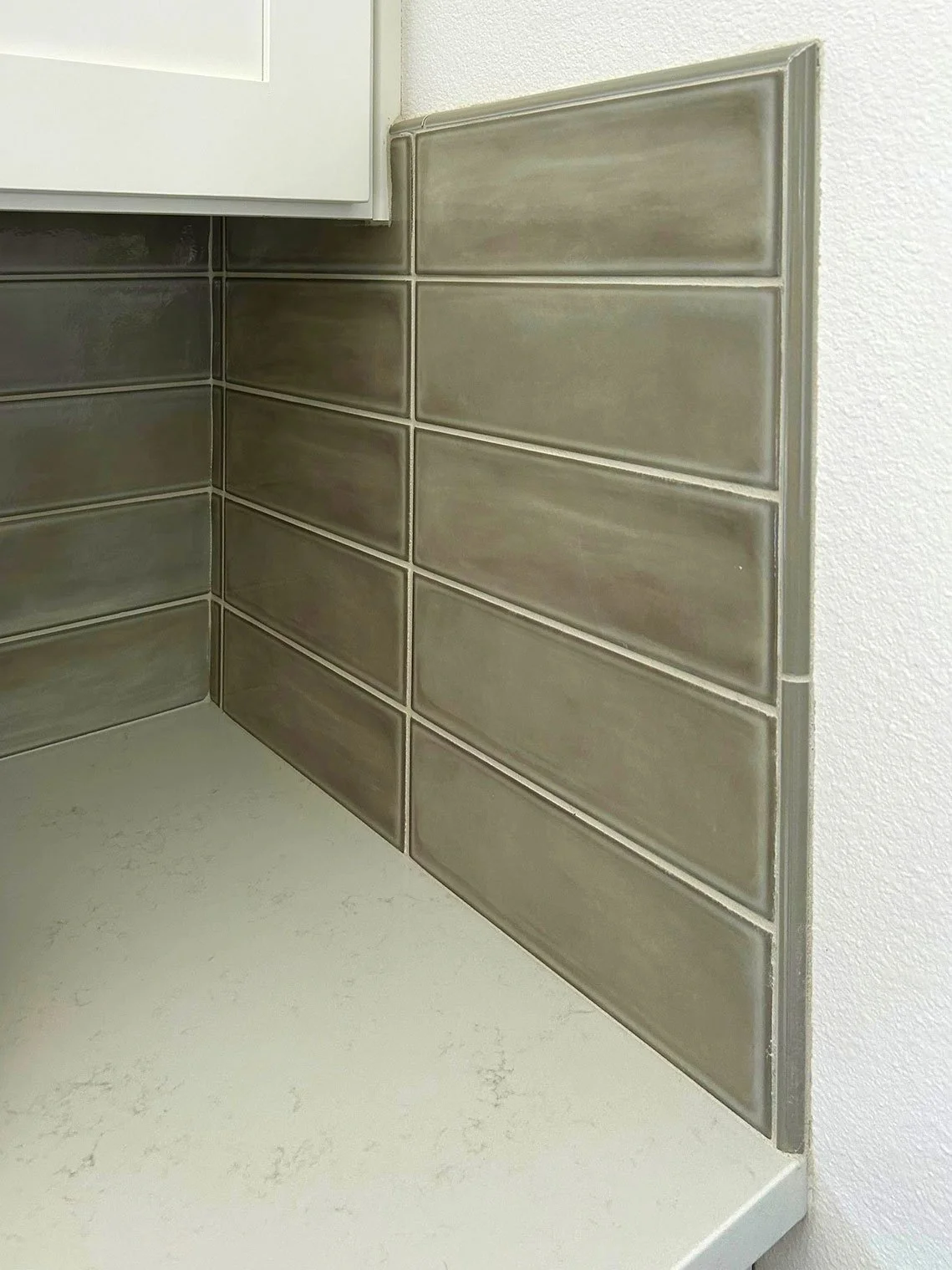 Close-up of a kitchen corner showing brown rectangular tile backsplash and white countertop in Bend, Oregon.