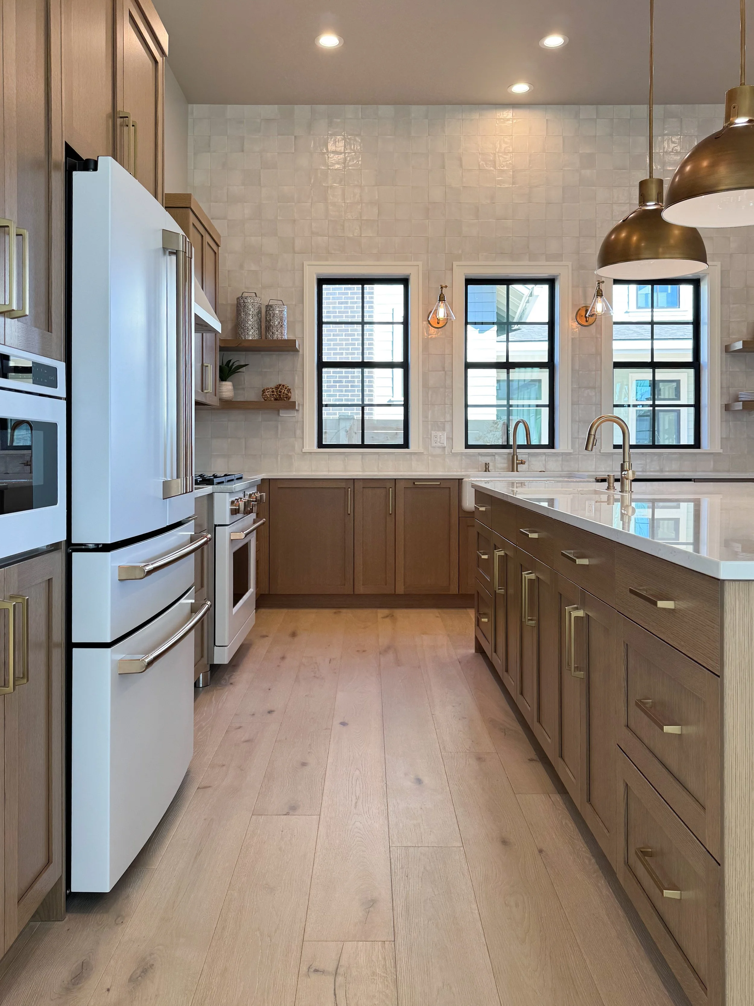 Modern kitchen in Bend, Oregon with wooden cabinets, white countertops, black-framed windows, and pendant lights.
