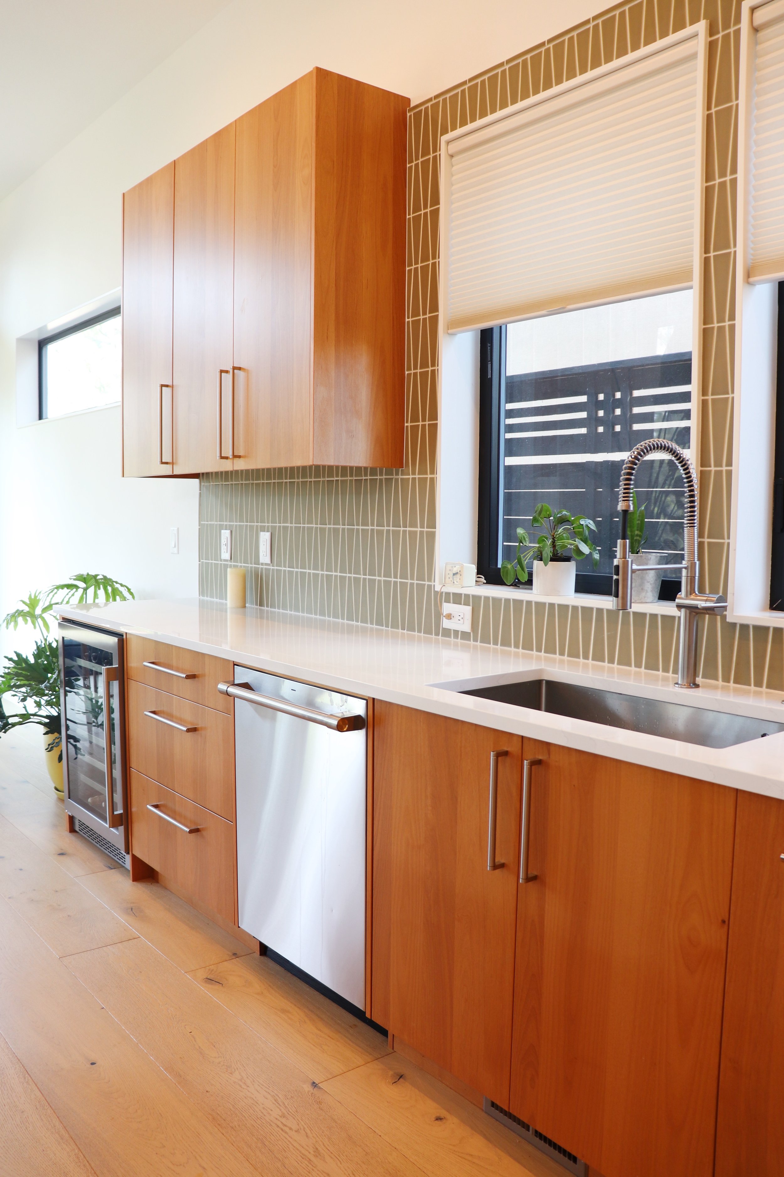 Modern kitchen in Bend, Oregon with wooden cabinets, a white countertop, a small wine cooler, and a window with a view outside.
