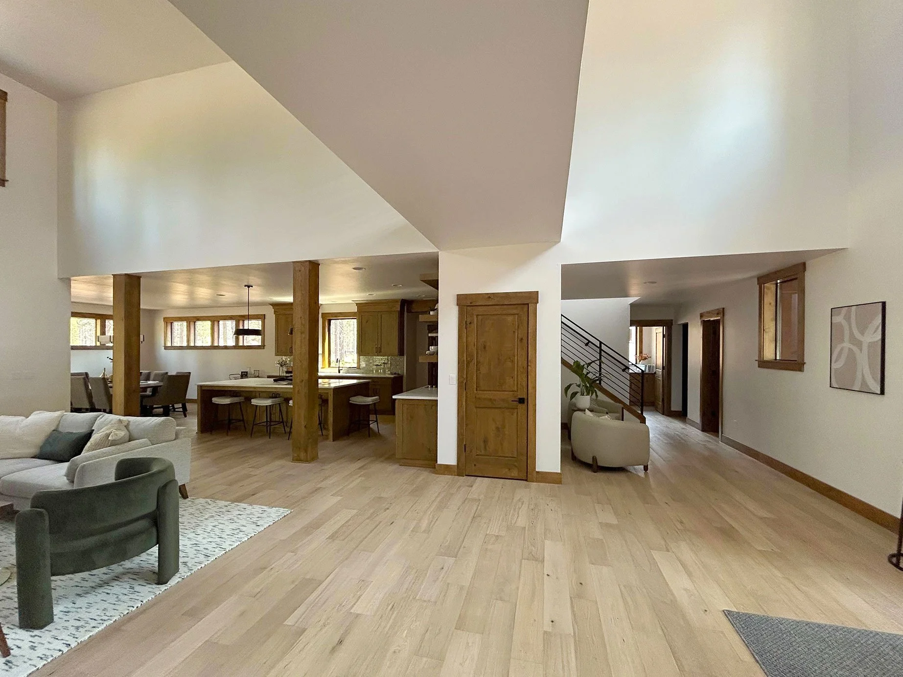 Open-concept living room and kitchen with wood flooring, white walls, and wooden accents, including doors and support beams in Bend, Oregon.